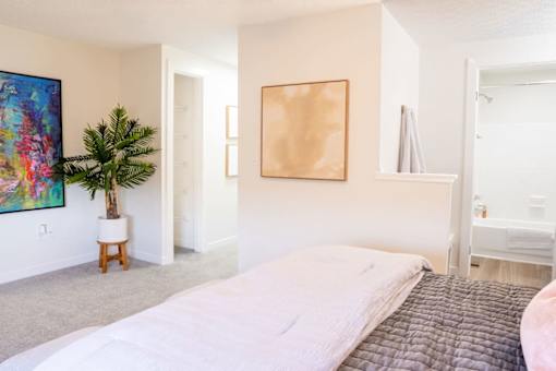 A bedroom with a large bed and a painting on the wall.