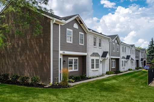 A row of houses with a blue sky and clouds in the background.