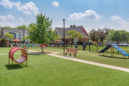 A playground with a red slide, a blue slide, and a brown bench.