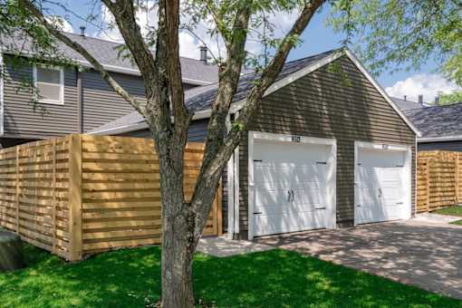 A house with a white garage door is surrounded by a green lawn.