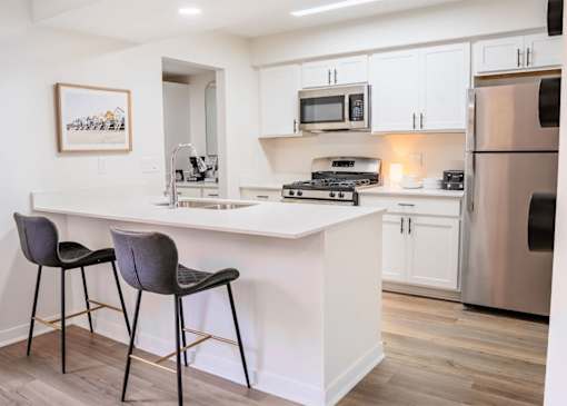 A kitchen with a white countertop and a fridge.