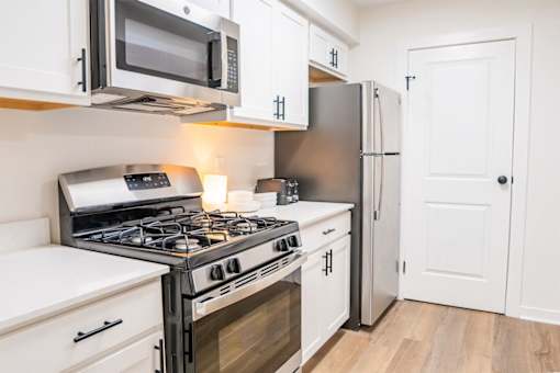 A modern kitchen with a stove, microwave, and refrigerator.