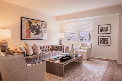 A living room with a grey couch, a coffee table, and a painting on the wall.