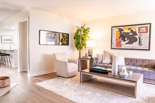 A living room with a white couch, a white chair, a coffee table, and a potted plant.
