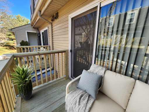 A small balcony with a couch and a potted plant.