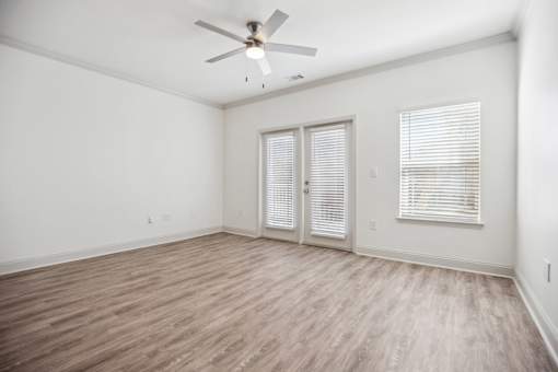 A room with a ceiling fan and wooden flooring.