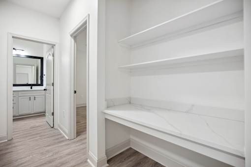 A white hallway with a mirror and a bench.