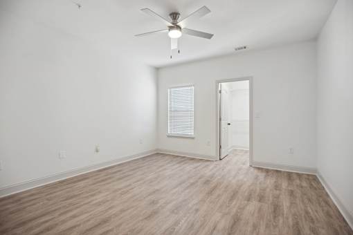 A room with a ceiling fan and wooden flooring.