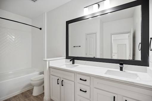 A bathroom with a white toilet, sink, and mirror.