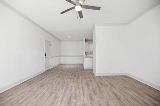 A room with a ceiling fan and light fixture, and a wooden floor.