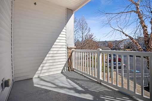 A white balcony with a metal railing and a white wall.