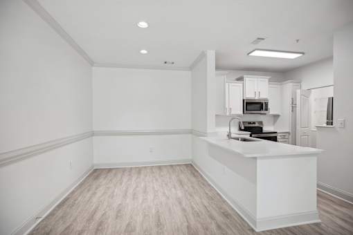 A kitchen with a white counter and wooden flooring.