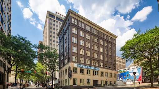 A street view of a city with a building that has a sign that says "Apartments for Lease".
