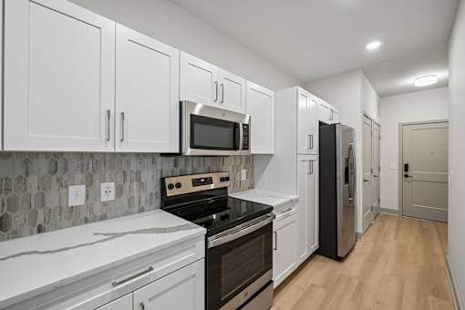 A kitchen with white cabinets and a black fridge.