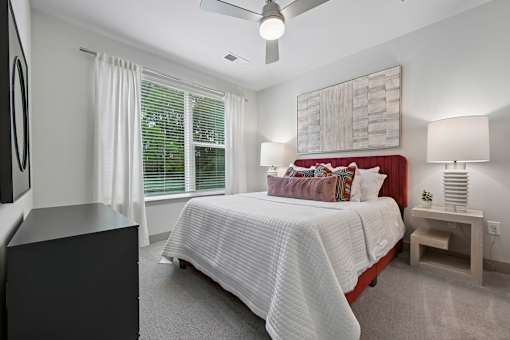 A bedroom with a bed, nightstand, and a ceiling fan.