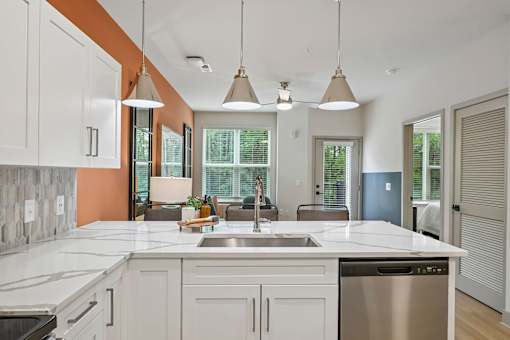 A kitchen with a white counter top and a stainless steel dishwasher.
