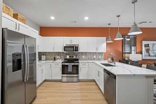 A modern kitchen with a refrigerator on the left and a sink on the right.