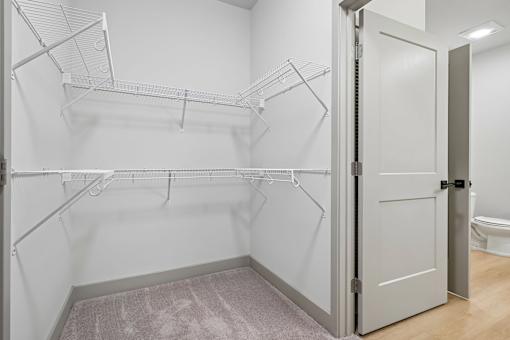 A white closet with a toilet in the background.