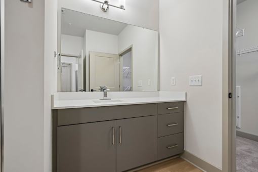 A bathroom with a sink, mirror, and cabinets.