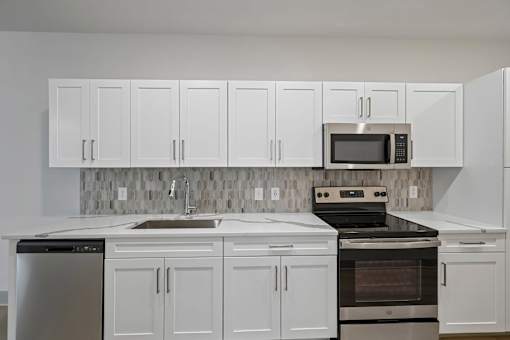 A kitchen with white cabinets and appliances.