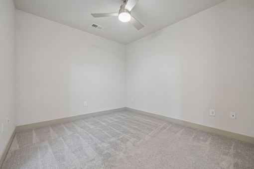 A room with a ceiling fan and carpeted floor.