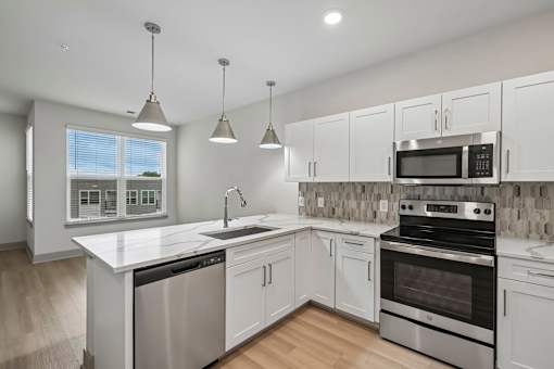 A modern kitchen with white cabinets and stainless steel appliances.