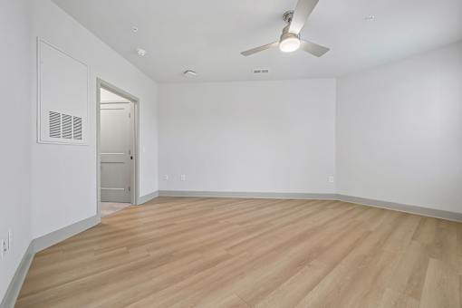 A room with a ceiling fan and wooden flooring.