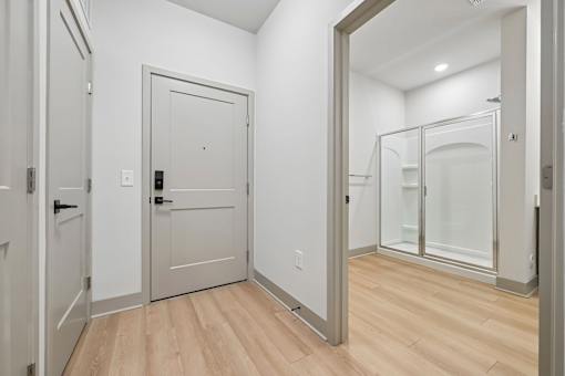A white door with a black handle is in a room with wood flooring.