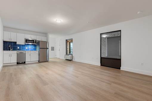 A kitchen with white cabinets and a wooden floor.