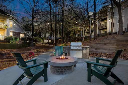 A fire pit in the middle of a patio surrounded by two chairs.