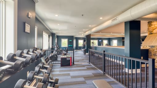 a fitness room with cardio machines and chairs at the bottom of a staircase