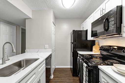 A kitchen with black appliances and white cabinets.