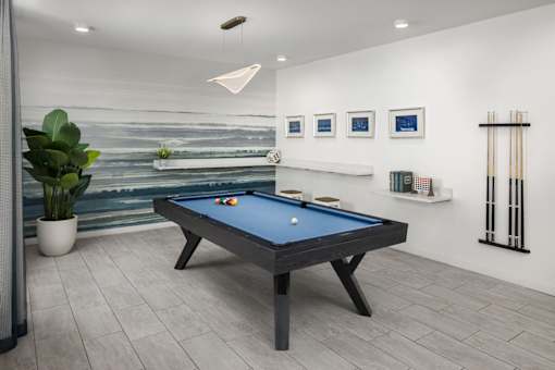 A pool table in a room with a painting on the wall.