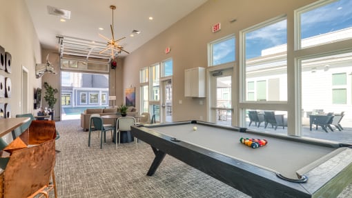 a community room with a pool table and a large window