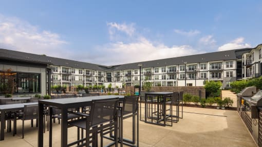 a patio with tables and chairs in front of an apartment building at Ainsworth, Richmond