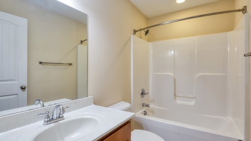 a bathroom with a white tub and a sink and a mirror
