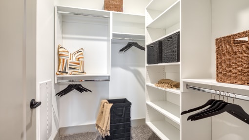 a walk in closet with white walls and shelves and a closet organizer with black glovesat Aura Stonebridge, Richmond, 23225