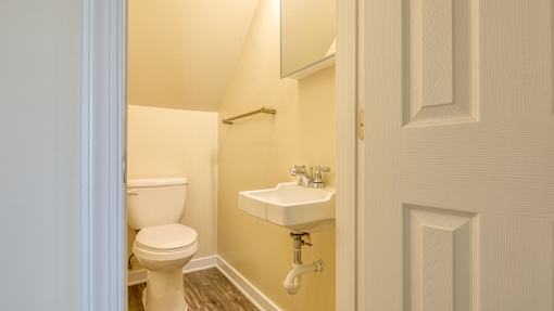 A white toilet sits next to a white sink in a small bathroom.