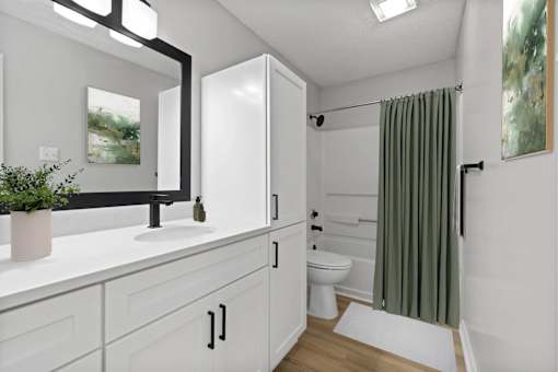 A white bathroom with a green shower curtain.