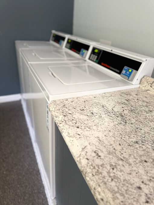 A white dishwasher is placed next to a granite countertop.