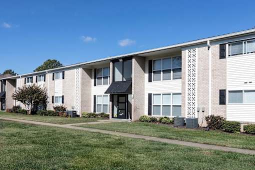 A building with a black awning is in the middle of a grassy area.