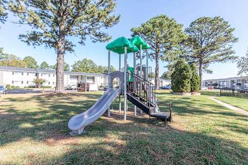 A playground with a green slide and a red slide.