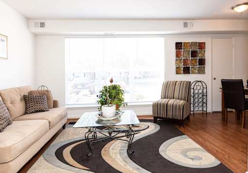 A living room with a couch, coffee table, and a striped chair.
