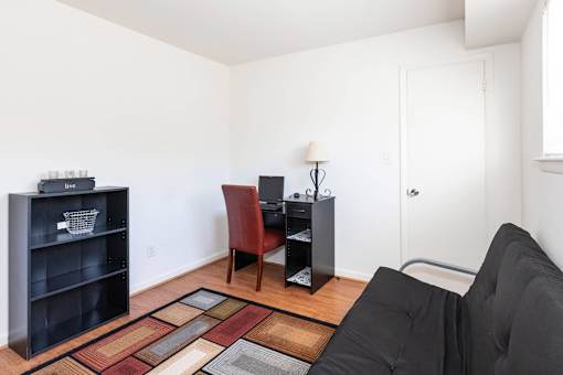 A living room with a black couch, a red chair, and a black bookshelf.