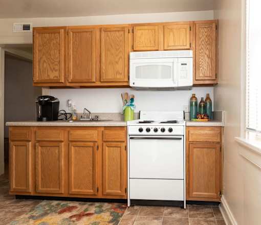 A kitchen with wooden cabinets and a white stove top oven.