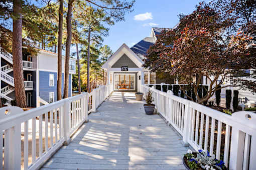 A white fence leads to a building with a balcony.