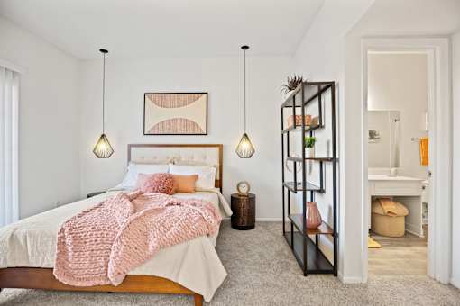 A bedroom with a bed, a shelf, and a lamp.