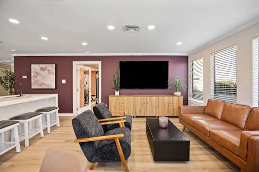 A living room with a grey armchair, a brown leather sofa, a wooden coffee table, and a white bench with black cushions.