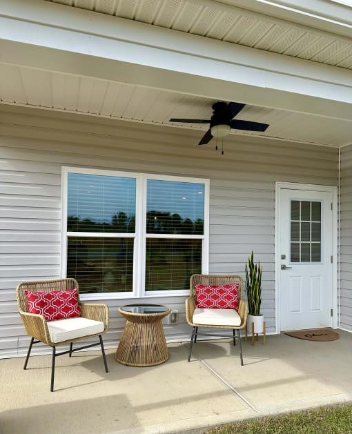 a front porch with chairs and a table and a ceiling fan