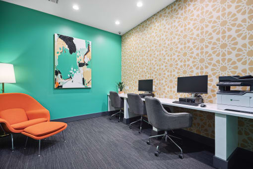 a office with a green wall and orange chairs and desks